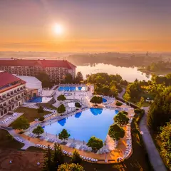Hotel Gołębiewski Mikołajki o wschodzie słońca. Widok na rozległy kompleks basenów i jezioro.