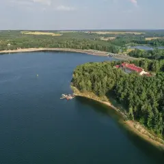Malownicze jezioro Chańcza otoczone lasem, z hotelem i pomostem.