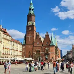 Tętniący życiem Rynek we Wrocławiu, z Ratuszem w centrum. Ludzie spacerują, podziwiając piękną starówkę wrocław.