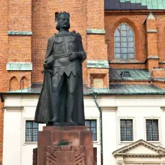Pomnik Bolesława Chrobrego, pierwszego króla polskiego, na tle ceglanej katedry.