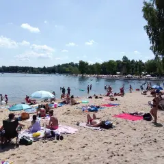 Słoneczny dzień nad zalewem Sosina. Ludzie odpoczywają na piaszczystej plaży, kąpią się i opalają.