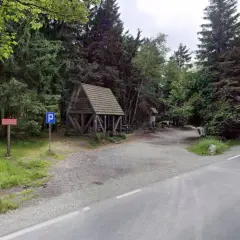 Drewniana wiata i parking przy leśnej drodze. To idealne miejsce na postój podczas wędrówki przez Lisia Przełęcz.