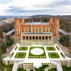 Imponujący Kamieniec Ząbkowicki zamek, otoczony parkiem i lasem, z widokiem na miasto.