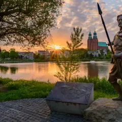 Pomnik wojownika na tle jeziora i katedry. Wschód słońca nad Gnieznem, pierwszą stolicą Polski.