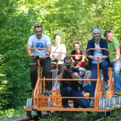 Rodzina na drezynach w Bieszczadach, ciesząca się zielenią i słońcem. Radość i wspólna przygoda na torach.
