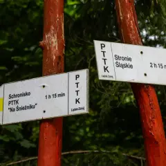 Znaki PTTK wskazują drogę do schroniska "Na Śnieżniku" (1h 15 min) i do Stronia Śląskiego (2h 15 min).
