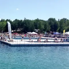 Słoneczny dzień na Balatonie w Trzebini. Ludzie odpoczywają na pływającym pomoście i w wodzie.