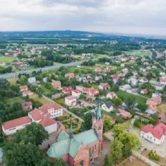 Widok z lotu ptaka na Wola Rzędzińska: kościół, domy, droga i tereny zielone.