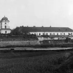 Zamek w Rzeszowie z wieżą i długim budynkiem, otoczony kamiennym murem.