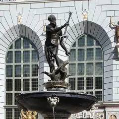 Fontanna Neptuna znajduje się w Gdańsku, przed fasadą budynku z arkadowymi oknami. Rzeźba przedstawia boga mórz na tle kamiennej architektury.