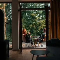 Para siedząca na zewnątrz przy kawie, z widokiem na las.