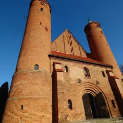 Imponująca ceglana świątynia w Brochowie z dwiema wieżami i łukowym portalem, pod błękitnym niebem.