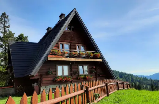 Drewniane schronisko na Maciejowej z kwitnącymi pelargoniami na balkonach i oknach. Otoczone zielenią i lasem, zaprasza na górskie wędrówki.