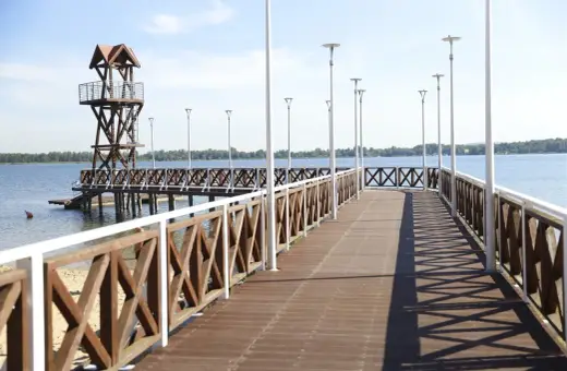 Drewniany pomost z wieżą ratowniczą nad jeziorem, idealne miejsce na wypoczynek nad wodą. Zbiornik Pogoria III zaprasza!