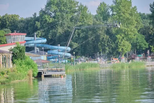 Zalew Zemborzycki w Lublinie: wodna zjeżdżalnia, plaża z ludźmi i zielone drzewa.