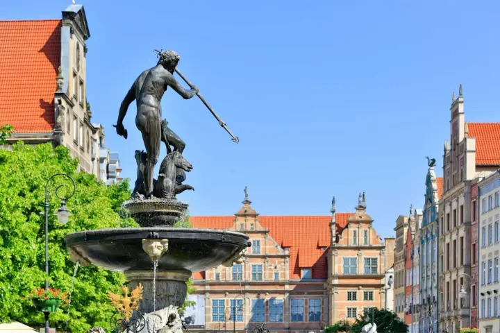 Fontanna Neptuna na Długim Targu w Gdańsku, z barwnymi kamienicami w tle.