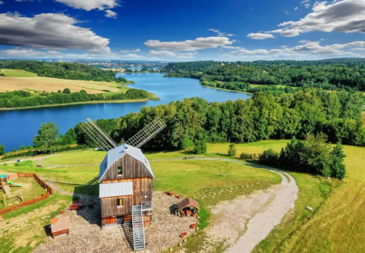Wiatrak na tle jeziora i lasów. Tak właśnie wyglądają Kaszuby, malowniczy region Polski.