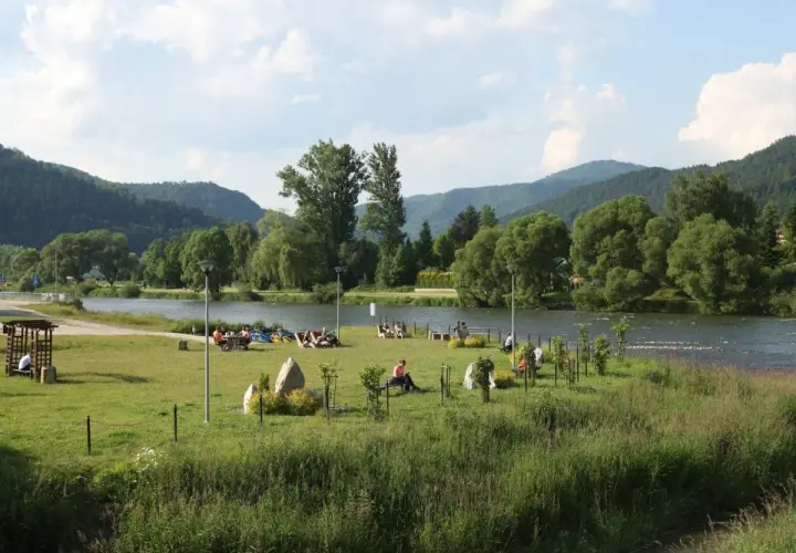 Relaks nad Dunajcem w Krościenku. Ludzie odpoczywają na trawie, w tle góry i rzeka. To świetne krościenko nad dunajcem atrakcje.