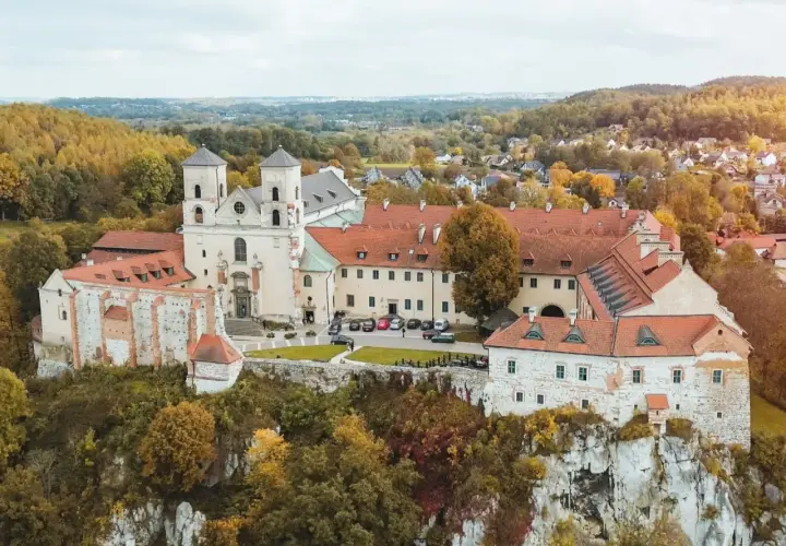 Najstarszy klasztor w Polsce, benedyktyńskie opactwo na skale, otoczone jesiennymi drzewami.