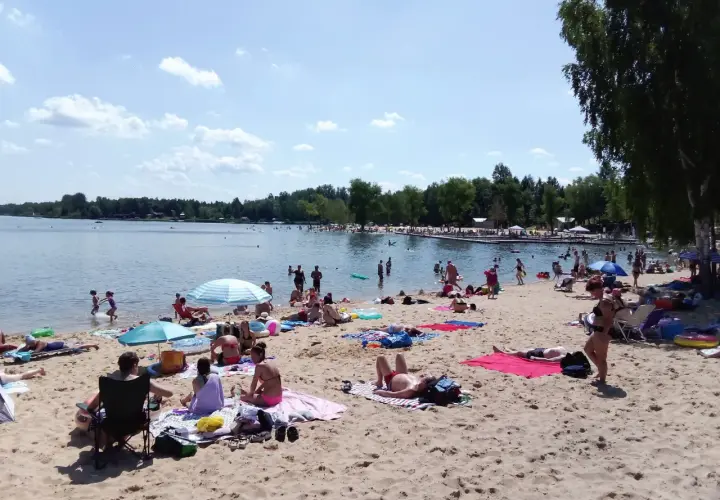 Słoneczny dzień nad zalewem Sosina. Ludzie odpoczywają na piaszczystej plaży, kąpią się i opalają.