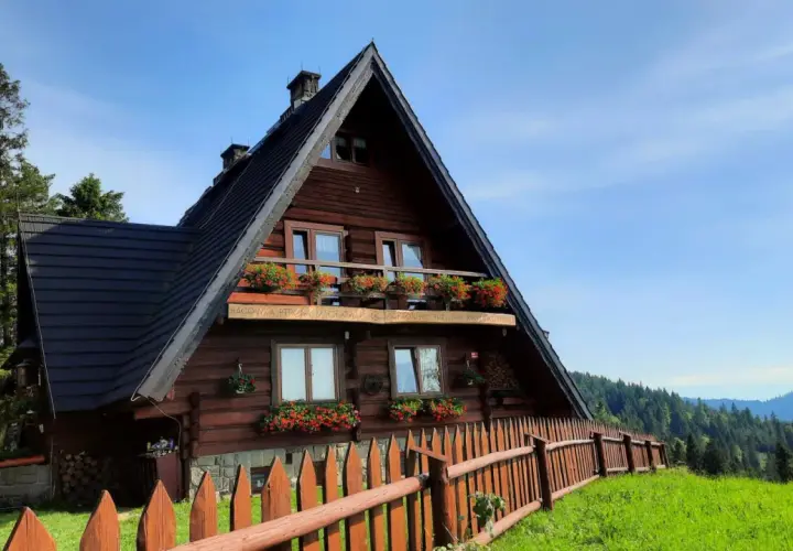 Drewniane schronisko na Maciejowej z kwitnącymi pelargoniami na balkonach i oknach. Otoczone zielenią i lasem, zaprasza na górskie wędrówki.