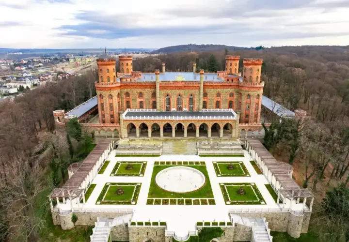 Imponujący Kamieniec Ząbkowicki zamek, otoczony parkiem i lasem, z widokiem na miasto.