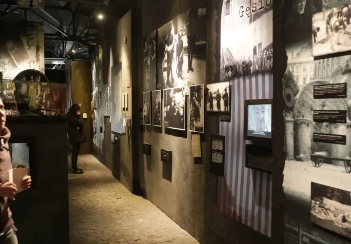 Wystawa w Muzeum Powstania Warszawskiego. Zwiedzający wpatrują się w historyczne fotografie i eksponaty, które budzą refleksje.