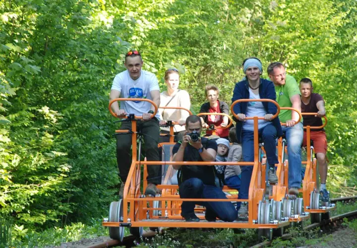 Rodzina na drezynach w Bieszczadach, ciesząca się zielenią i słońcem. Radość i wspólna przygoda na torach.