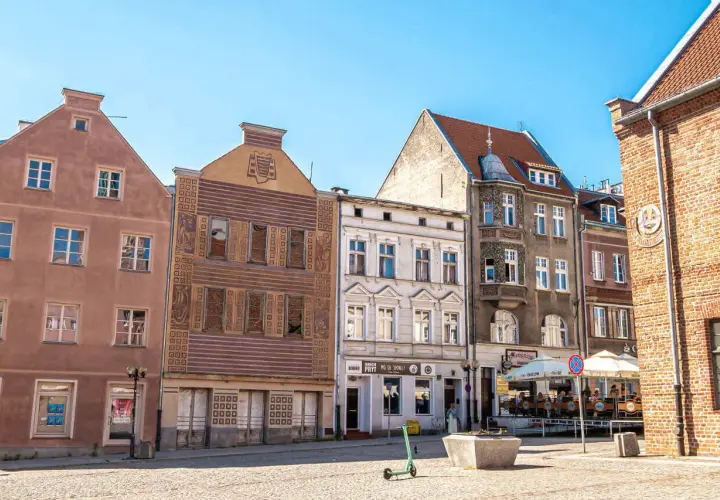 Kamienice na rynku w Olsztynie, głównym mieście Warmii. Słoneczny dzień, brukowany plac.