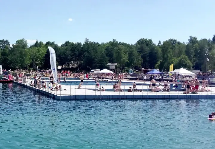 Słoneczny dzień na Balatonie w Trzebini. Ludzie odpoczywają na pływającym pomoście i w wodzie.