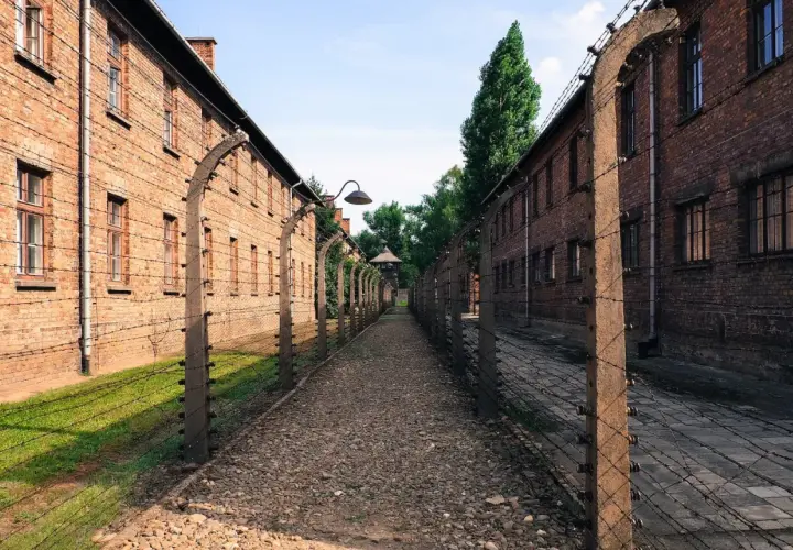 Droga między ceglanymi budynkami Auschwitz, otoczona drutem kolczastym. Miejsce, gdzie komendant Auschwitz podejmował swoje decyzje.