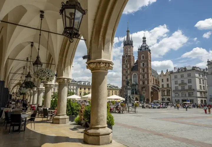 Podcienia Sukiennic w Krakowie, z widokiem na Rynek Główny i Kościół Mariacki. Stare miasto kraków tętni życiem.