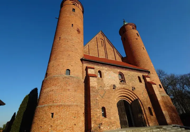 Imponująca ceglana świątynia w Brochowie z dwiema wieżami i łukowym portalem, pod błękitnym niebem.