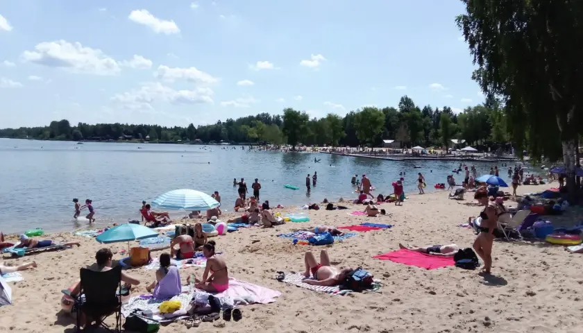 Słoneczny dzień nad zalewem Sosina. Ludzie odpoczywają na piaszczystej plaży, kąpią się i opalają.