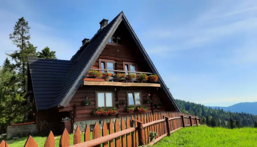 Drewniane schronisko na Maciejowej z kwitnącymi pelargoniami na balkonach i oknach. Otoczone zielenią i lasem, zaprasza na górskie wędrówki.