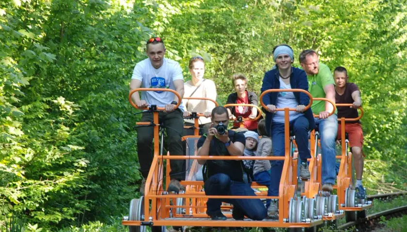 Rodzina na drezynach w Bieszczadach, ciesząca się zielenią i słońcem. Radość i wspólna przygoda na torach.