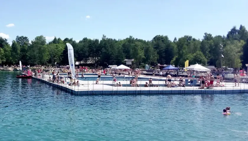 Słoneczny dzień na Balatonie w Trzebini. Ludzie odpoczywają na pływającym pomoście i w wodzie.