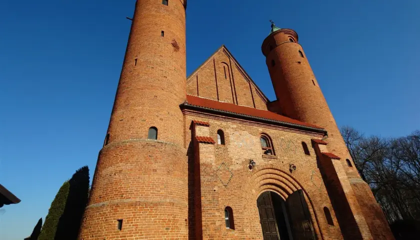 Imponująca ceglana świątynia w Brochowie z dwiema wieżami i łukowym portalem, pod błękitnym niebem.