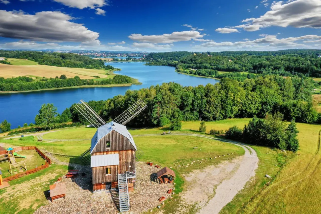 Wiatrak na tle jeziora i lasów. Tak właśnie wyglądają Kaszuby, malowniczy region Polski.