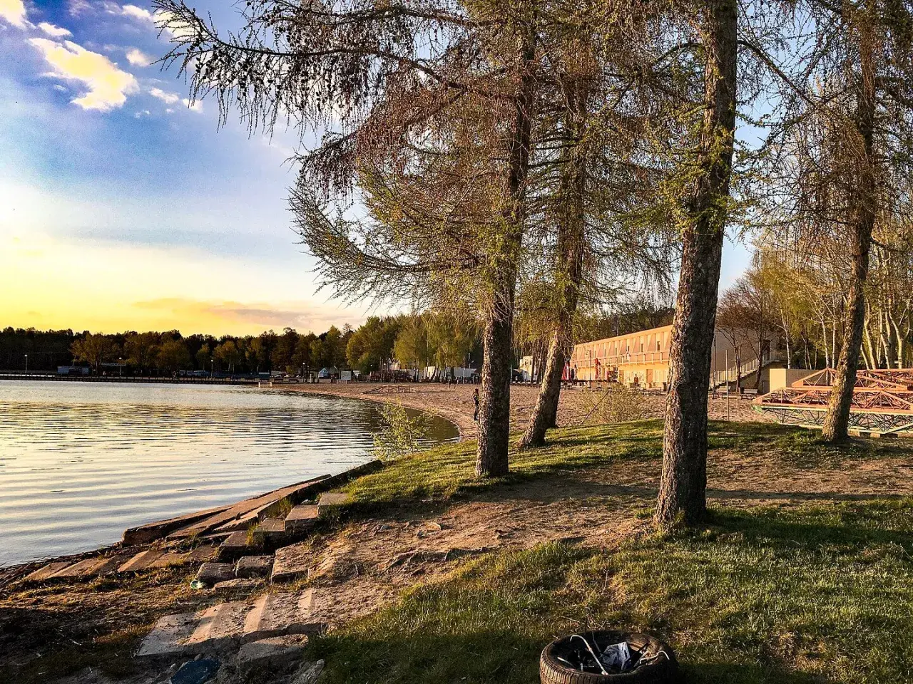 Zachód słońca nad jeziorem, plaża i drzewa. Skorzęcin atrakcje turystyczne czekają na odkrycie.