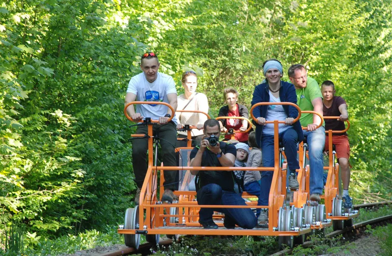 Rodzina na drezynach w Bieszczadach, ciesząca się zielenią i słońcem. Radość i wspólna przygoda na torach.