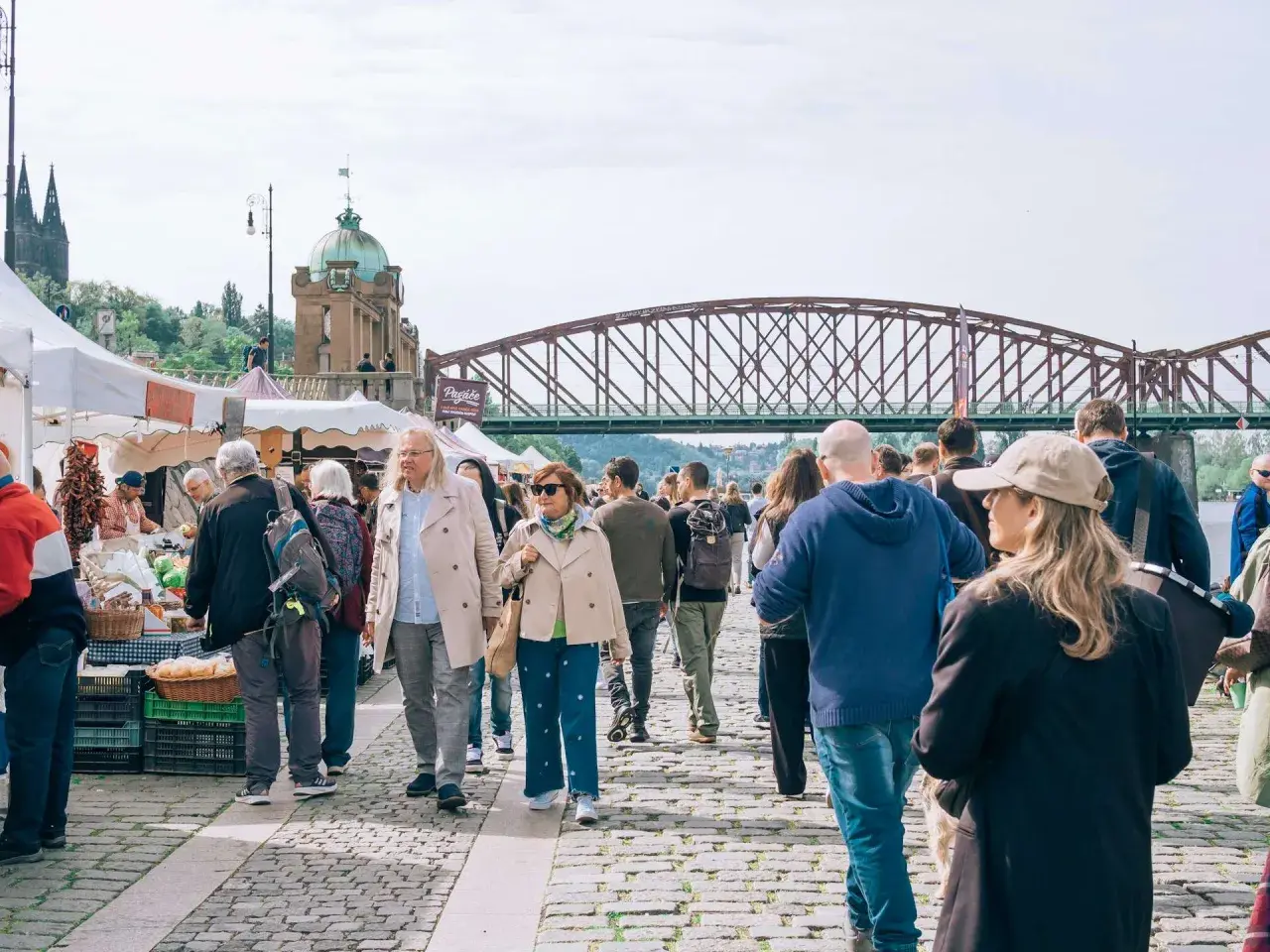Tłum ludzi na targu, most w tle. Może to być scena z jednego z miast w rankingu miast w Polsce.