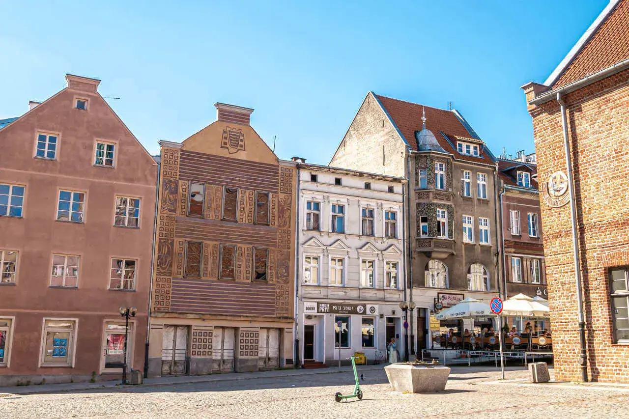 Kamienice na rynku w Olsztynie, głównym mieście Warmii. Słoneczny dzień, brukowany plac.