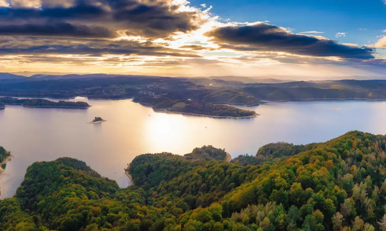 Zachód słońca nad jeziorem Solina. Widać zalesione wzgórza, wyspy i zatoczki. Idealne miejsce na odkrywanie atrakcji Solina i okolice.