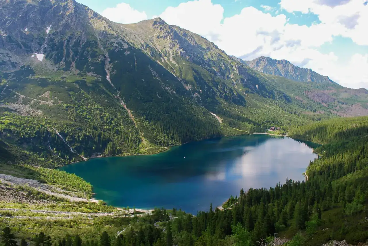 Morskie Oko, Tatry. Głębokość jeziora ukryta w turkusowej toni, otoczonej stromymi, zalesionymi zboczami gór.