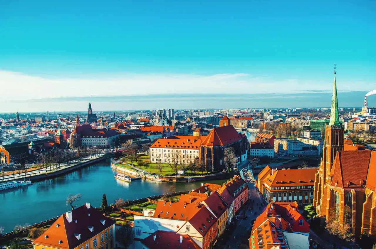Widok na Ostrów Tumski we Wrocławiu, jeden z najpiękniejszych polskich miast, z rzeką i zabytkową architekturą.