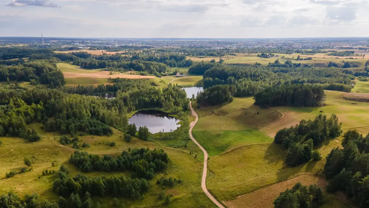 Malownicze jeziora i lasy na Suwalszczyźnie, z drogą wijącą się pośród zieleni. W oddali widać miasto.
